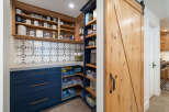 Discover the ultimate pantry organization with this beautifully designed space, featuring custom navy blue cabinetry and open shelving.