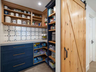 Discover the ultimate pantry organization with this beautifully designed space, featuring custom navy blue cabinetry and open shelving.