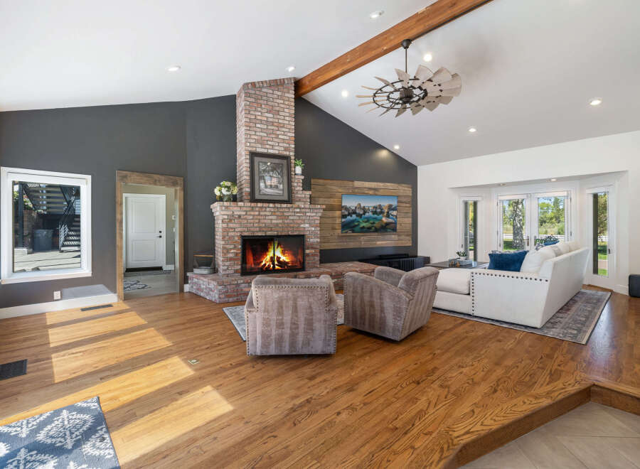 Experience the warmth of this inviting living room, featuring a stunning floor-to-ceiling brick fireplace as the centerpiece.
