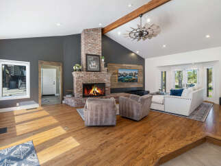 Experience the warmth of this inviting living room, featuring a stunning floor-to-ceiling brick fireplace as the centerpiece.