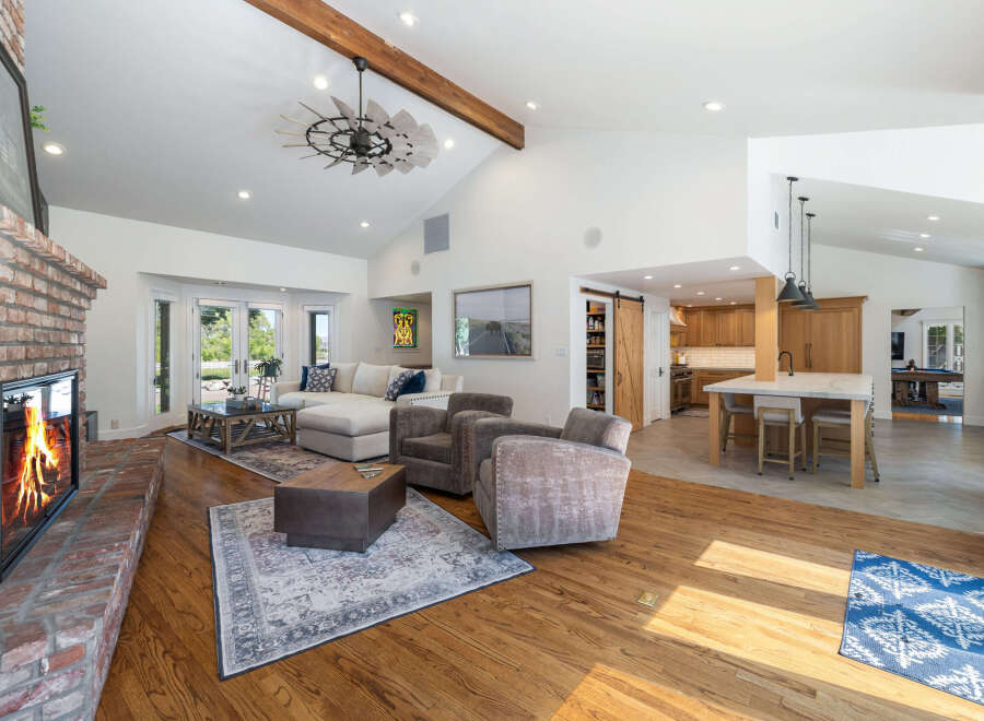 Experience luxurious living in this spacious open-concept home, featuring a stunning brick fireplace and vaulted ceilings with exposed beams.