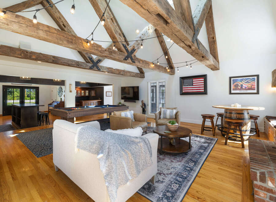 Experience rustic charm in this spacious entertainment room, featuring exposed wooden beams and a cozy fireplace.