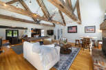 Experience rustic charm in this spacious entertainment room, featuring exposed wooden beams and a cozy fireplace.