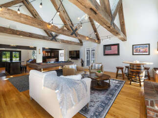Experience rustic charm in this spacious entertainment room, featuring exposed wooden beams and a cozy fireplace.