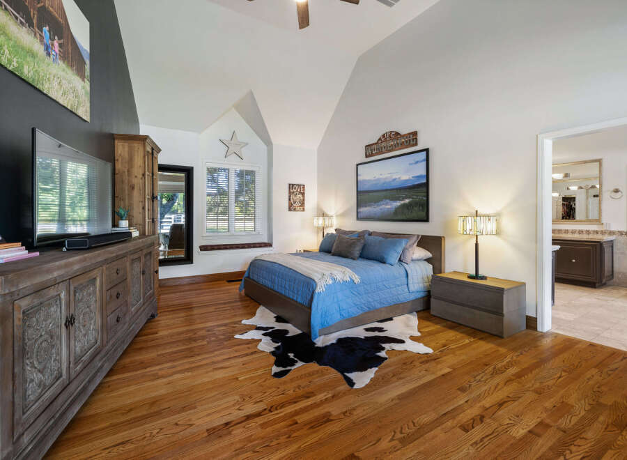 Experience rustic charm in this master bedroom featuring a vaulted ceiling and a large picture window with a charming star accent.