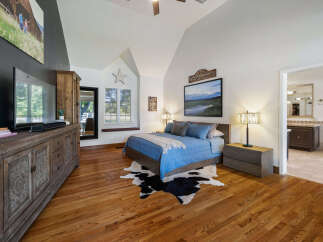 Experience rustic charm in this master bedroom featuring a vaulted ceiling and a large picture window with a charming star accent.