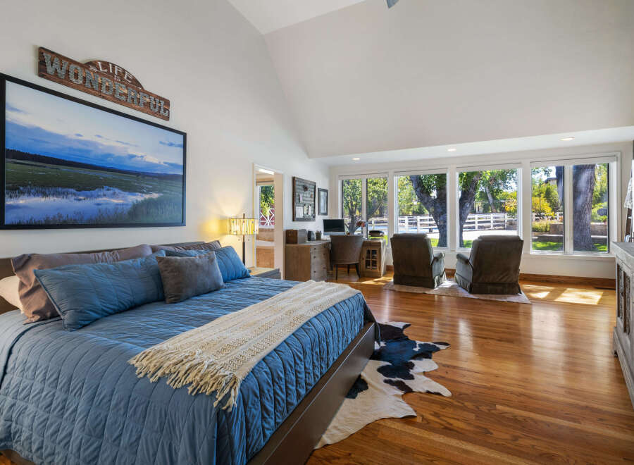 Experience rustic charm in this spacious bedroom featuring a large king-size bed with plush blue bedding and a cozy throw.