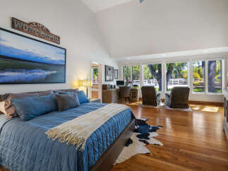 Experience rustic charm in this spacious bedroom featuring a large king-size bed with plush blue bedding and a cozy throw.