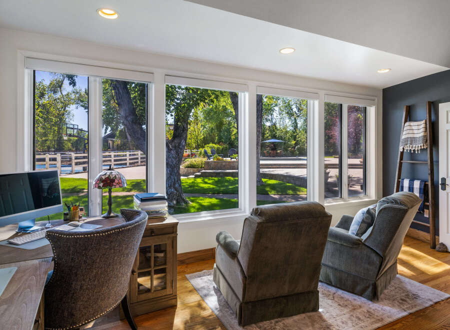 This home office offers a productive and relaxing atmosphere with a large desk, comfortable seating, and stunning views of the backyard oasis.