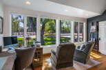 This home office offers a productive and relaxing atmosphere with a large desk, comfortable seating, and stunning views of the backyard oasis.