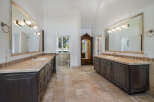 This spacious master bathroom features dual vanities with marble countertops and dark wood cabinetry, offering ample storage and a luxurious feel.