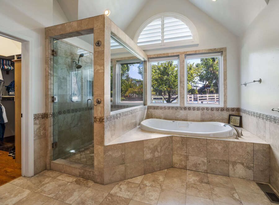 Indulge in luxury in this stunning master bathroom featuring a spacious walk-in shower with elegant tilework and a deep soaking tub.