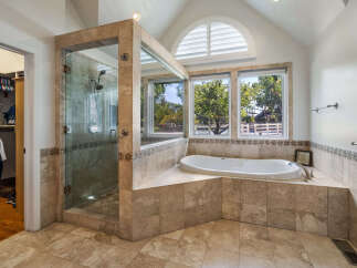 Indulge in luxury in this stunning master bathroom featuring a spacious walk-in shower with elegant tilework and a deep soaking tub.