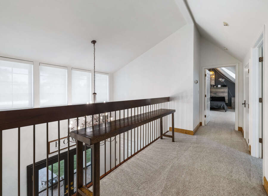 This spacious hallway features a dark wood railing and a long bench, perfect for adding decorative touches or extra seating.