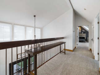 This spacious hallway features a dark wood railing and a long bench, perfect for adding decorative touches or extra seating.