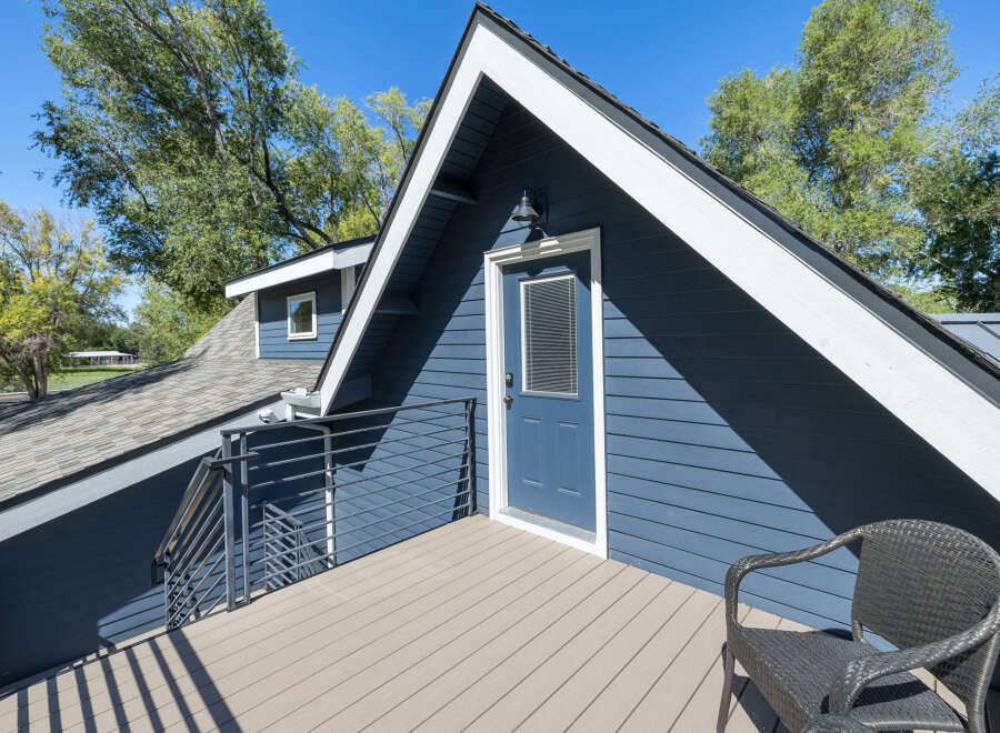 Enjoy outdoor living on this charming deck, complete with a modern wicker chair perfect for relaxing.
