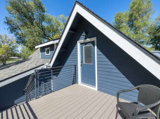 Enjoy outdoor living on this charming deck, complete with a modern wicker chair perfect for relaxing.