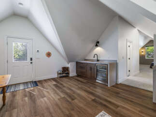 Discover this charming space featuring a convenient wet bar with a mini-fridge and ample cabinet storage, perfect for entertaining.