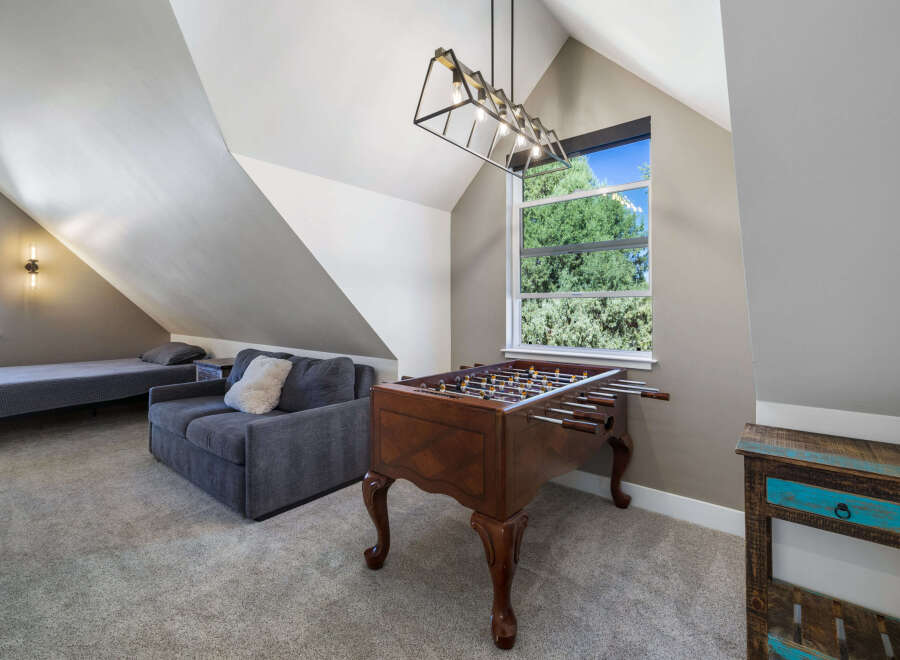 This spacious attic room offers a versatile living space with a comfortable sofa and a twin bed, perfect for guests or a cozy retreat.
