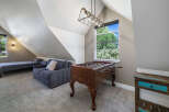 This spacious attic room offers a versatile living space with a comfortable sofa and a twin bed, perfect for guests or a cozy retreat.