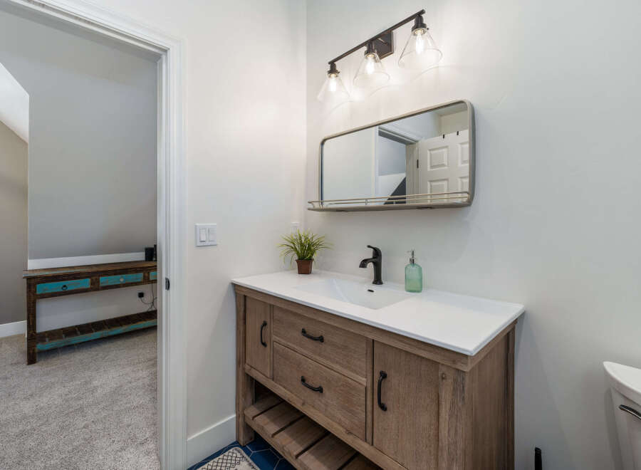 This bathroom features a stylish wooden vanity with a white countertop and a modern black faucet.