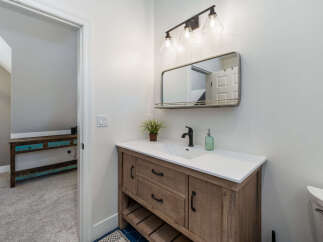 This bathroom features a stylish wooden vanity with a white countertop and a modern black faucet.