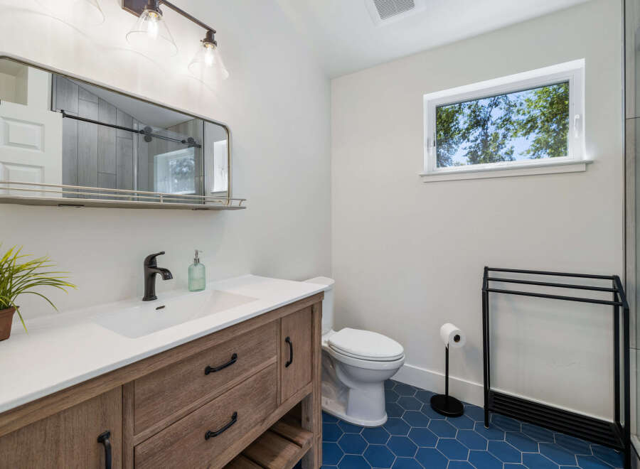 This modern bathroom features a stylish wooden vanity with a white countertop and a sleek black faucet.