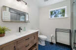 This modern bathroom features a stylish wooden vanity with a white countertop and a sleek black faucet.