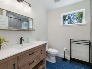 This modern bathroom features a stylish wooden vanity with a white countertop and a sleek black faucet.
