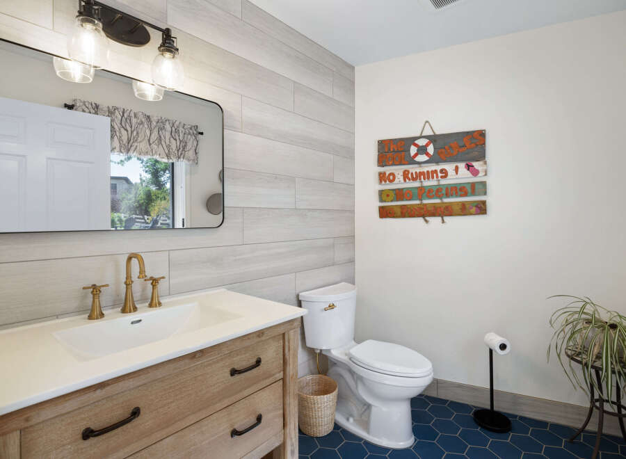 This charming bathroom features a rustic wooden vanity with a white undermount sink and elegant brass fixtures.