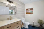 This charming bathroom features a rustic wooden vanity with a white undermount sink and elegant brass fixtures.
