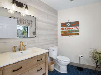 This charming bathroom features a rustic wooden vanity with a white undermount sink and elegant brass fixtures.