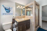 This charming bathroom features a spacious vanity with ample counter space and storage, complemented by a large mirror with decorative lighting.