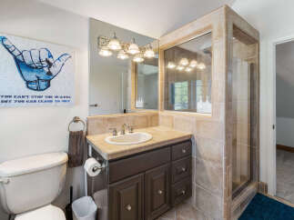 This charming bathroom features a spacious vanity with ample counter space and storage, complemented by a large mirror with decorative lighting.