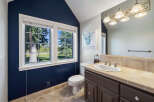 This charming bathroom features a deep navy accent wall that complements the warm-toned tile flooring and backsplash.
