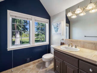 This charming bathroom features a deep navy accent wall that complements the warm-toned tile flooring and backsplash.