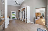 This spacious entryway features a large built-in white storage unit with glass-fronted cabinets and open shelving, perfect for organizing shoes and displaying decor.