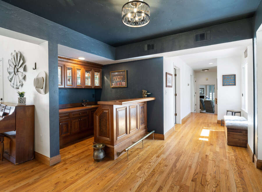 Step into this inviting home featuring a custom wooden bar perfect for entertaining, complemented by elegant cabinetry and a striking dark blue accent wall.