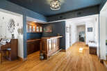 Step into this inviting home featuring a custom wooden bar perfect for entertaining, complemented by elegant cabinetry and a striking dark blue accent wall.