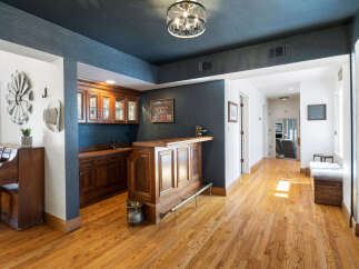Step into this inviting home featuring a custom wooden bar perfect for entertaining, complemented by elegant cabinetry and a striking dark blue accent wall.