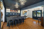 Step into this stunning home bar, featuring a dark wood bar with ample seating and a backdrop of shelves stocked with liquor.