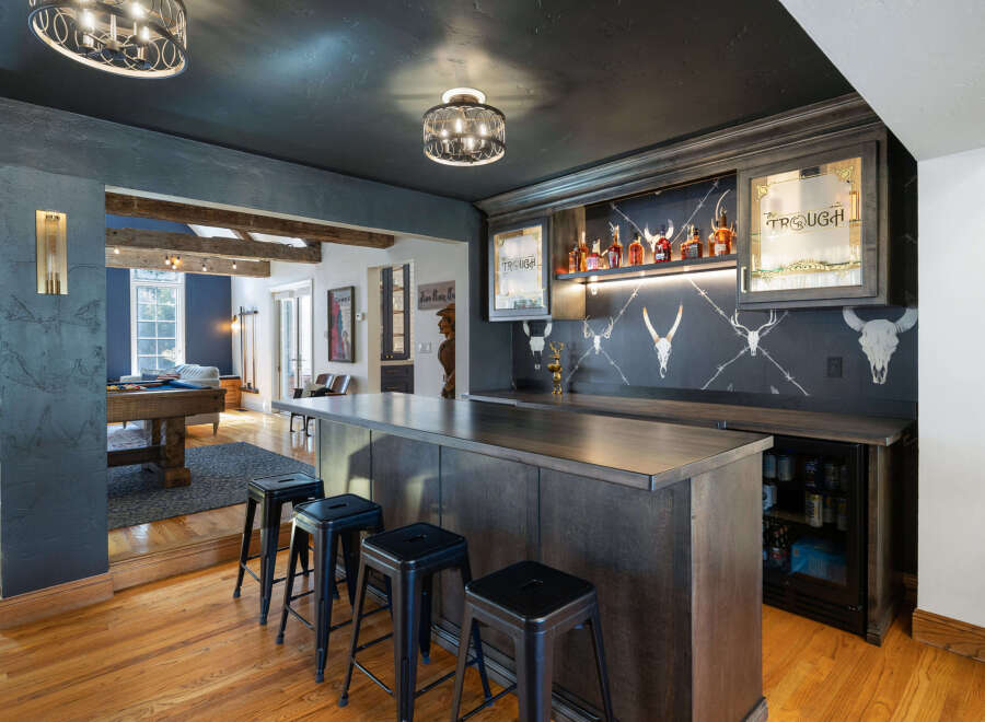 Experience ultimate entertainment in this stunning home bar area, featuring a sleek dark wood bar with ample seating and a built-in beverage cooler.
