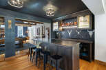Experience ultimate entertainment in this stunning home bar area, featuring a sleek dark wood bar with ample seating and a built-in beverage cooler.