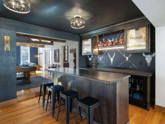 Experience ultimate entertainment in this stunning home bar area, featuring a sleek dark wood bar with ample seating and a built-in beverage cooler.