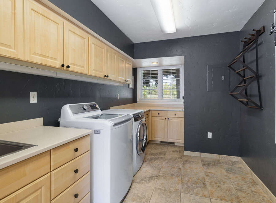 This laundry room boasts ample storage with light wood cabinets lining the walls and a spacious countertop.