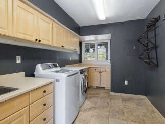 This laundry room boasts ample storage with light wood cabinets lining the walls and a spacious countertop.