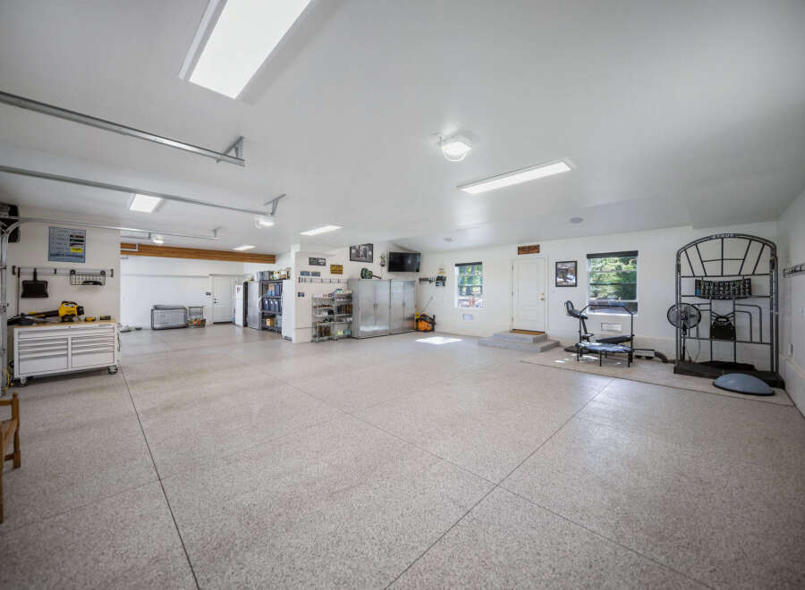 This spacious garage offers ample storage with multiple cabinets and shelving units, perfect for organizing tools and equipment.