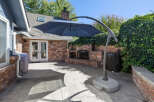 Enjoy outdoor living with this spacious patio featuring a built-in brick fireplace and a large cantilever umbrella for ample shade.