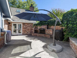 Enjoy outdoor living with this spacious patio featuring a built-in brick fireplace and a large cantilever umbrella for ample shade.