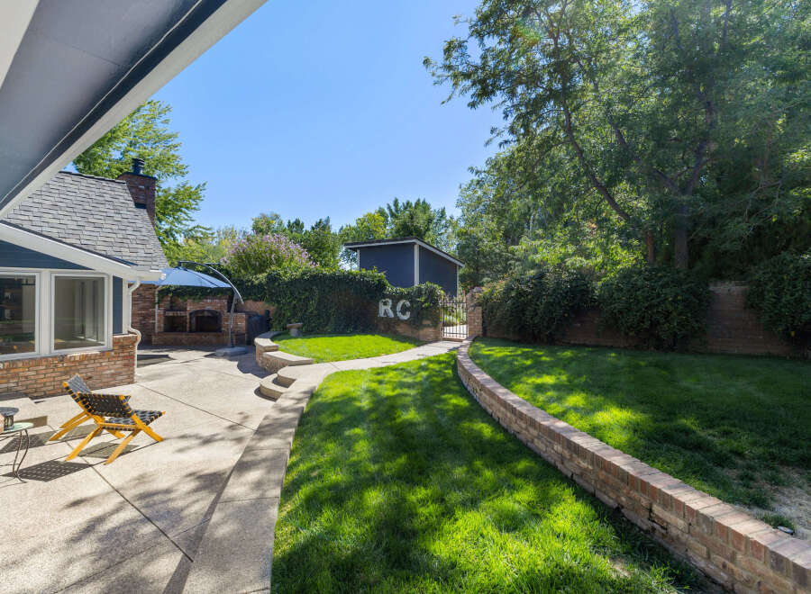 Enjoy outdoor living in this spacious backyard featuring a charming brick patio and a lush green lawn perfect for recreation.